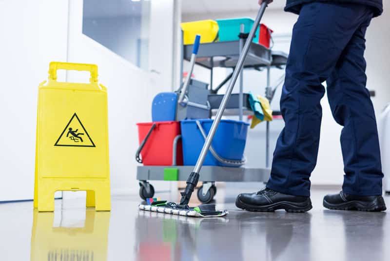 Worker janitor Mopping Floor In Office with trolley